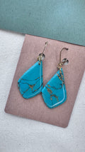 Turquoise polymer clay earrings with gold veining and a glossy resin finish, irregular shape with gold hooks on kraft card